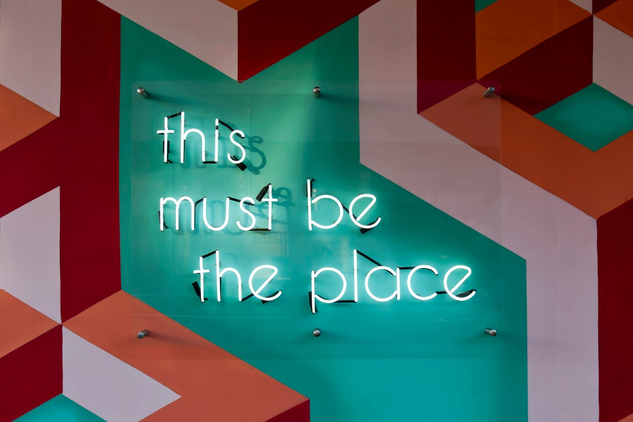 Services-02 Colorful geometric wall featuring a glowing neon sign with an inspirational quote.